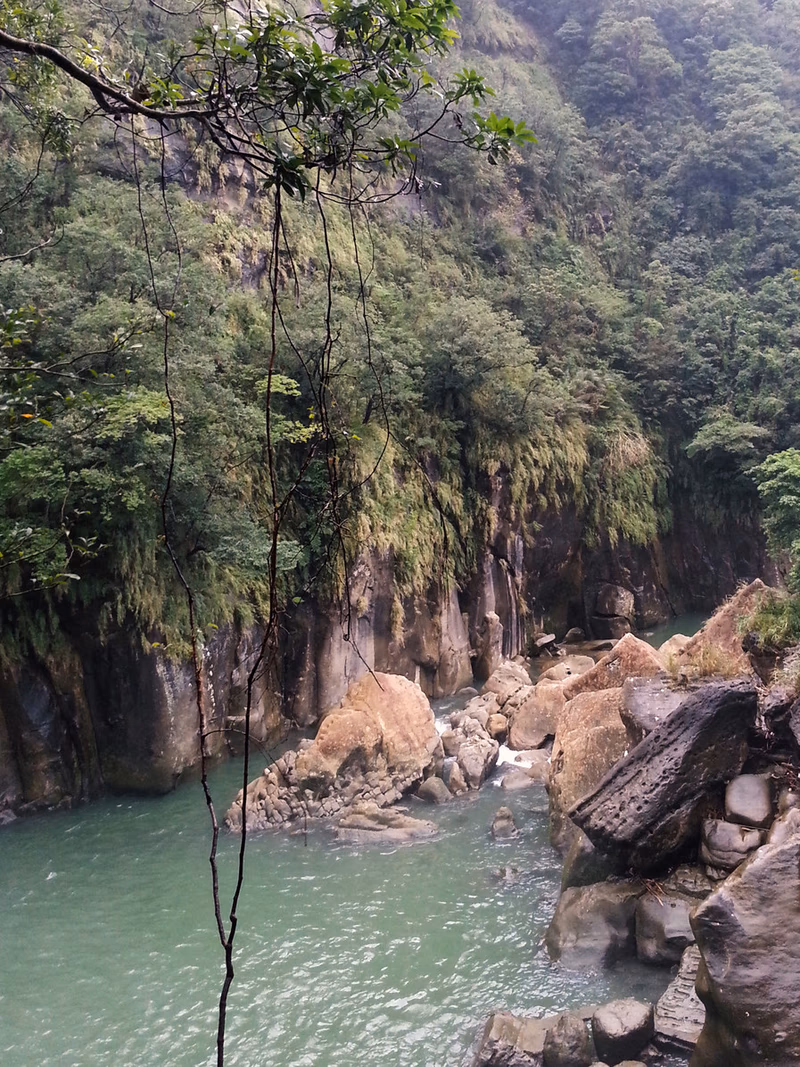 A serene river valley with lush greenery and towering mountains